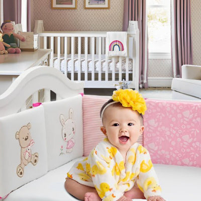 Fillette souriante dans Tour de lit bébé sérénité