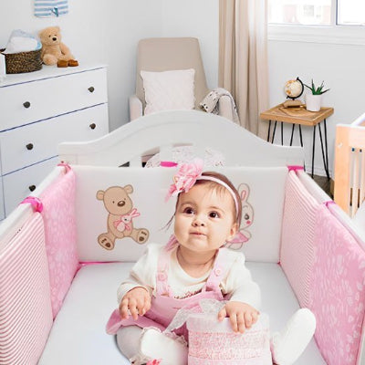 Petite fille avec jouet regardant devant dans Tour de lit bébé sérénité