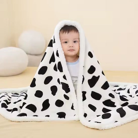 Couverture bébé en vache enroulé sur un bébé assis