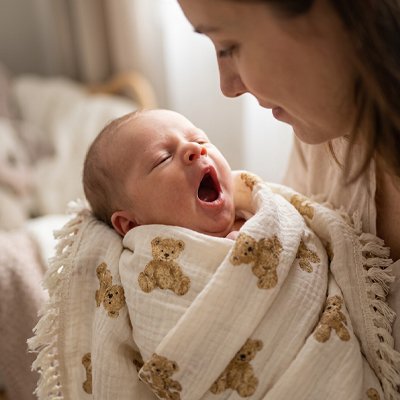 Couverture bébé enroulé sur bébé baillant dans les mains de maman