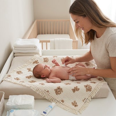 Couverture bébé sur laquelle une maman change la couche son bébé